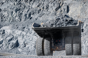 Massive Mining Dump Truck Transporting Rocks in Rugged Terrain at Quarry © Parilov