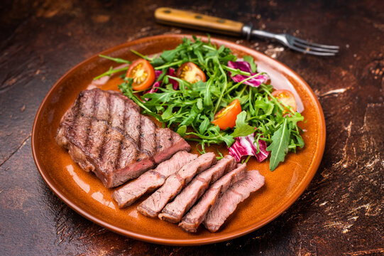 Grilled Australian Oyster Top blade steak with salad on a plate. brown background. top view