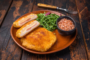 Chicken Fried cordon bleu cutlet on plate with salad. wooden background. top view