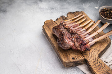 Grilled Rack of lamb, mutton meat chop steaks on wooden board. grey background. top view