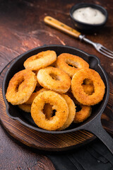 Crispy Fried onion rings, delicious snack in a pan. brown background. top view