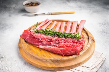 Uncooked rack of lamb, raw mutton chops on wooden board. grey background. top view