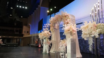 This video showcases a beautifully decorated wedding ceremony backdrop, featuring an abundance of white flowers and cascading greenery. The setup includes delicate string lights 