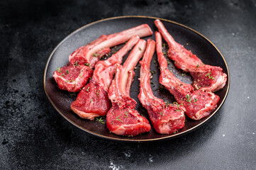 Fresh mutton chops, raw lamb meat cutlets on a plate. black background. top view