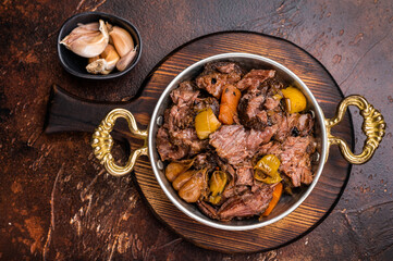 Slow cooked Beef Cheek, Braised meat with vegetables in a skillet. brown background. top view