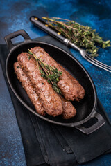 Grilled Cevapcici Sausage, roasted Cevapi from mince beef and pork meat in a skillet. blue background. top view