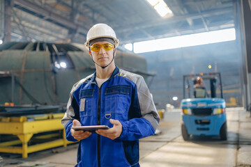 Caucasian male adult engineer with tablet computer in industrial shipyard environment