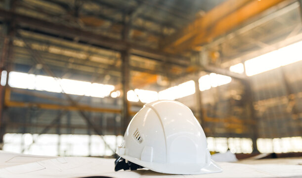 Shipyard safety: hard hat on industrial blueprints in cargo port setting