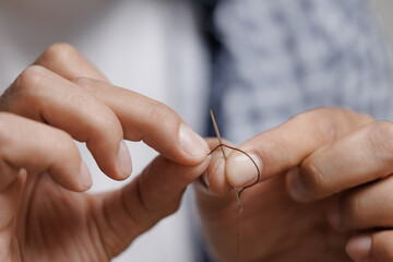 Close-up of hands sewing leather with needle and thread for skin craft