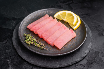 Vibrant tuna sashimi arranged on a plate, showcasing its rich color and delicate texture for an exquisite meal. black background. top view