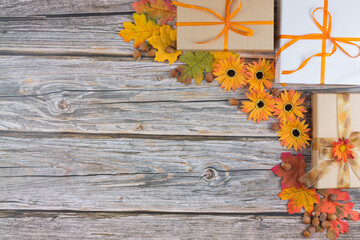 Autumn composition with gift boxes leaves, flowers and hazelnuts on wooden table, top view, copy space