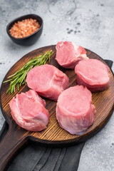 Beautifully cut raw pork medallions for tenderloin meat, waiting to absorb your favorite marinades for a flavorful feast. grey background. top view