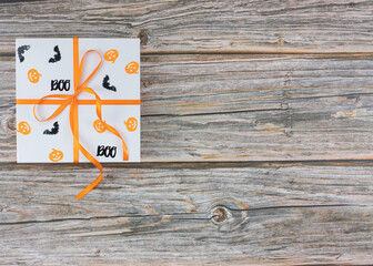 White gift box with pumpkins and bats on wooden table top view copy space