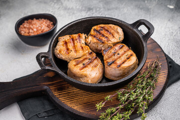 Juicy grilled pork medallions steaks, perfectly seared tenderloin meat for a flavorful bite, ideal for any gourmet meal. grey background. top view
