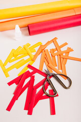 Strips of colored paper, scissors and glue to make paper garlands vertical view