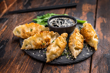 Fried Gyoza on plate with sauce, Japanese Dumplings with shrimps and vegetables. wooden background. top view