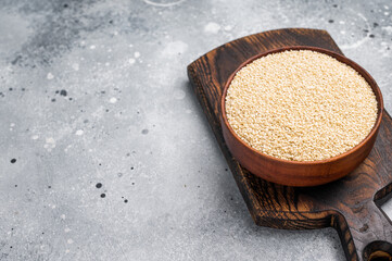 White sesame seeds in a wooden bowl. grey background. top view