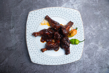 Sticky BBQ Chicken Drumsticks lollipops with Hot Peppers on a plate top view of snack