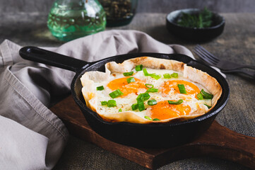 Homemade scrambled eggs in pita bread with herbs in a frying pan on the table