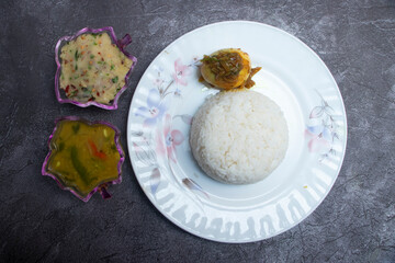 Bangladeshi Fish Curry Set with Steamed Rice, mashed potato and boiled egg in plate on a Dark Background top view of restaurant food