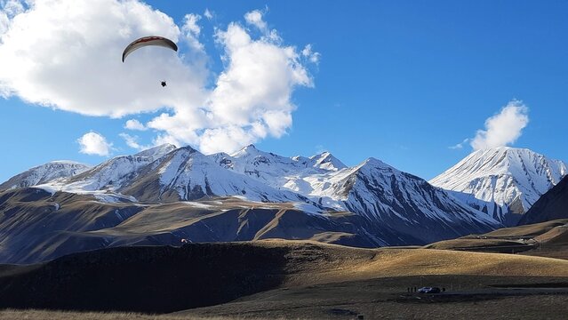 Vista panor&aacute;mica con alguien haciendo parapente en la ruta militar georgiana camino a Kazbegi desde Tbilisi - Georgia