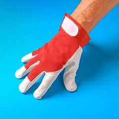 A man's hand wearing a red work glove set against a vibrant blue background