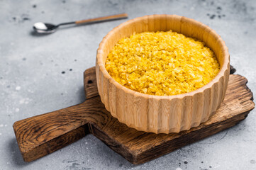 Millet flakes in wooden bowl, rolled millet for porridge and muesli. grey background. top view