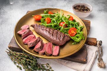 Grill Goat steak, roasted tenderloin fillet meat with salad. grey background. top view