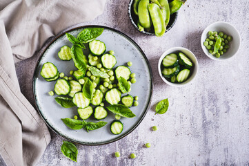 Antioxidant salad of fresh cucumbers, green peas and basil on a plate on the table top view