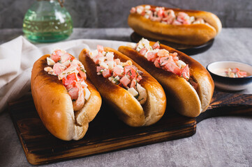Delicious hot dogs in fried buns with tomato, egg and shrimp salad on a board