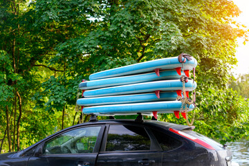Several stand up paddleboards are stacked on top of a black car, ready for a fun recreation at the...