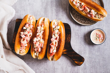 Delicious hot dogs in fried buns with tomato, egg and shrimp salad on a board top view