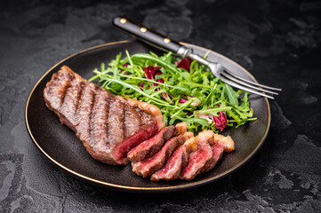 BBQ roast Rump Cap beef steak, Brazilian Picanha with salad on a plate. black background. top view