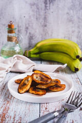 Fried plantain banana slices on a plate on the table vertical view