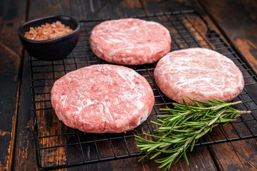 Frozen Meat patties ready for grilling, forcemeat of pork and beef for burgers. wooden background. top view