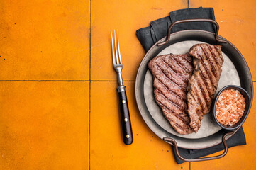 Grilled Denver steak, perfectly seared with beautiful grill marks, showcasing its juicy tenderness and rich flavor. orange background. top view