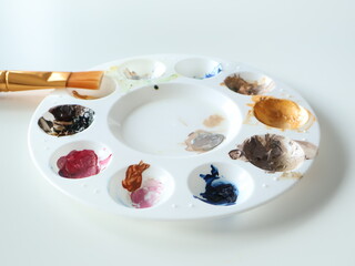 Artist Palette with Colorful Paints and Brush on a White Background. A vibrant artist's palette featuring various colors with a golden brush, showcasing creativity and art.