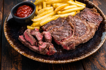 Dinner with grilled Chuck eye roll steak and french fry on a plate. wooden background. top view