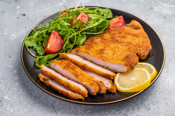 Fried Weiner schnitzel steak, veal breaded meat with salad on a plate. grey background. top view