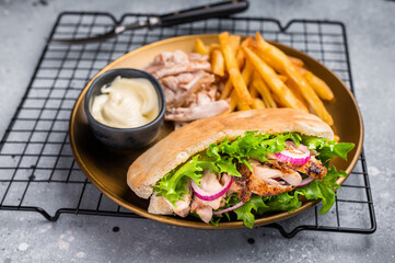 Grilled shawarma sandwich, Doner kebab with grilled meat in pita bread on a plate with french fry. grey background. top view