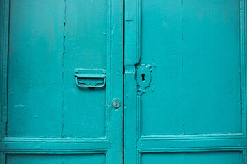 Puerta antigua de madera pintada en color turquesa con cerradura oxidada