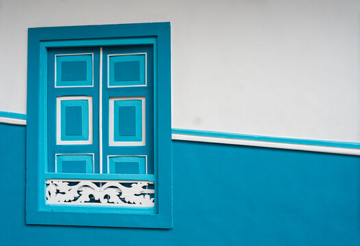 Ventana colonial azul turquesa con marco blanco en fachada tradicional