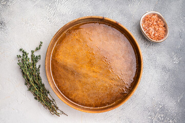 Chicken Bouillon or Broth  in a wooden plate. white background. top view