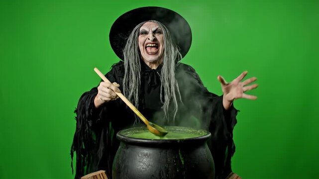 Menacing Witch Stirring Bubbling Cauldron - A cackling witch stirs a bubbling green potion in a cauldron. She is wearing a black robe and witch's hat against a bright green screen.
