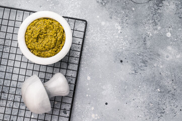 Pesto sauce, Iitalian spread with green basil in bowl. grey background. top view.