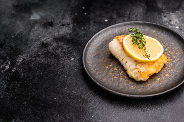 Roast Halibut fish loin fiilet on plate. Black background. top view