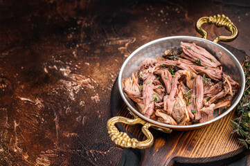 Close-up of succulent pulled brisket piled high on a rustic wooden board, garnished with fresh herbs, delicious meal. brown background. top view