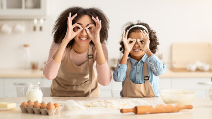 Fooling Around In The Kitchen. Portrait of smiling African American woman and little girl making...