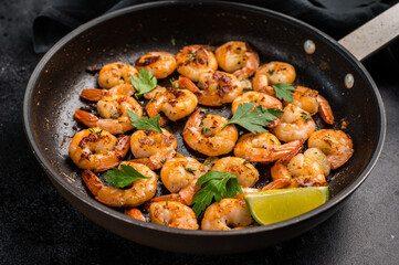 Fried Shrimps Prawns with garlic and butter in a skillet. Black background. Top view