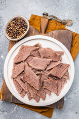 Corned sliced beef meat in a plate. gray background. top view